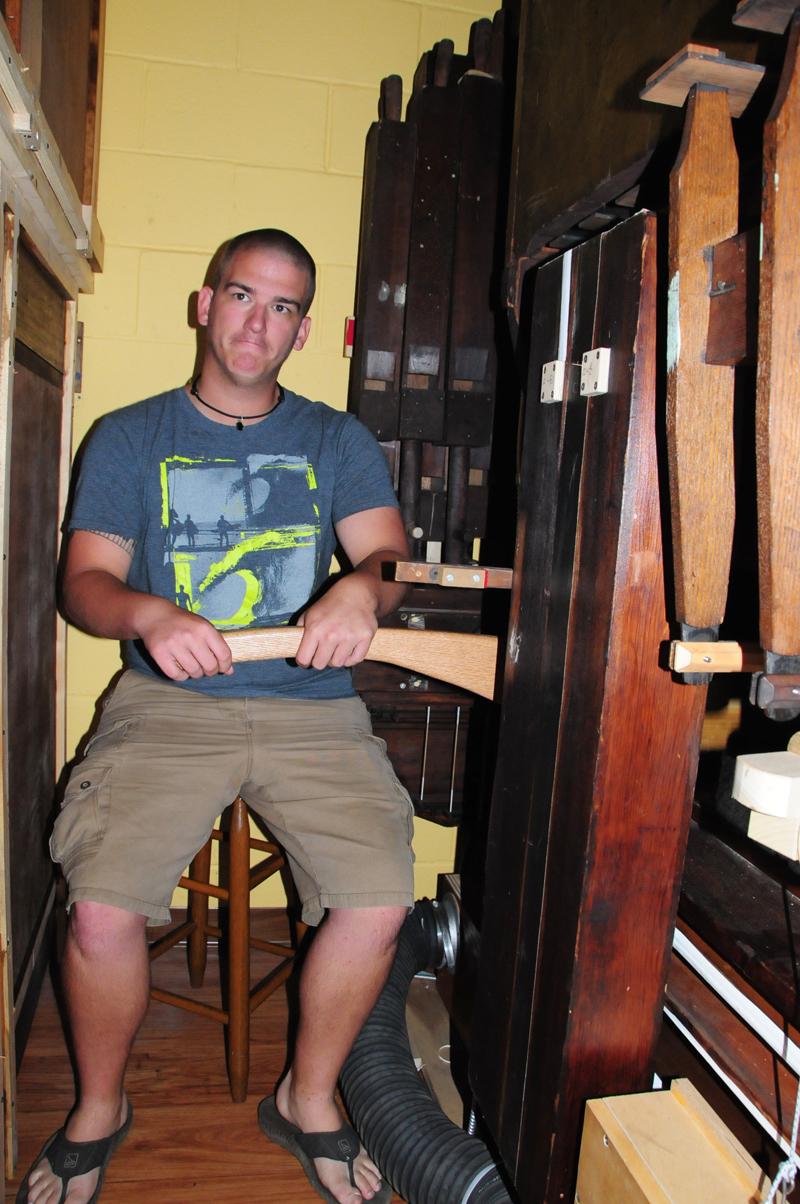 Jordan Hines helps with Dr. Wesley Roberts'  performance by going inside the organ to  pumpthe hand lever for air to reach the  pipes. (CU Photo by Drew Tucker)