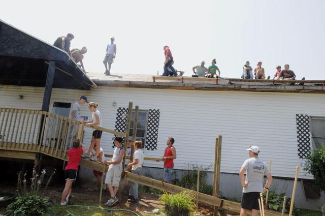 A group of volunteers from Brainerd United Methodist Church in Chattanooga, Tenn., Lynn Haven United Methodist Church in Panama City, Fla., First United Methodist Church in Panama City and Mt. Vernon Baptist Church in Boone, N.C., under the direction of Kentucky Heartland Outreach interns Lindsay Jones, Collin Johnson and Amanda Mosier, build a deck and ramp and replace a roof on a home near Cave City, Ky., during a week-long summer camp with KHO. (Campbellsville University Photo by Ashley Zsedenyi)