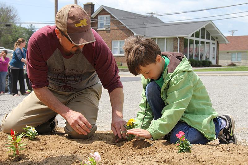 Elementary school students in the surrounding area, including second grader Noah Skaggs, left, attended Campbellsville University's Earth Day festivities, which included planting flowers with Rob Roberts, right, director of grounds and landscape development. (Campbellsville University Photo by Rachel DeCoursey)