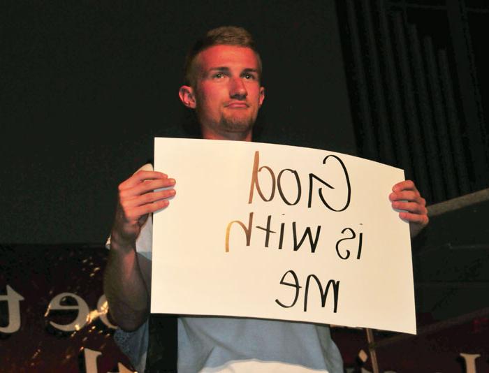 Zach Napier, Campbellsville University sophomore and FCA camp huddle leader, shares a piece of his testimony displayed on poster board, during worship. (Campbellsville University Photo by Josh Christian) 