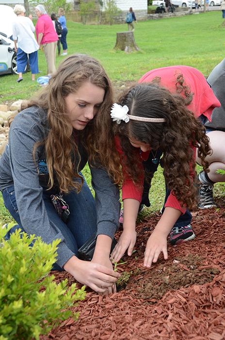 Raven Johnson, on right, helps a student from Kentucky Christian Academy to plant a sapling during the Earth Day ceremony at Campbellsville University. (Campbellsville University Photo by Tomomi Sato) 